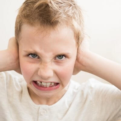 Does my child have sensory processing disorder? Boy with hands over ears.